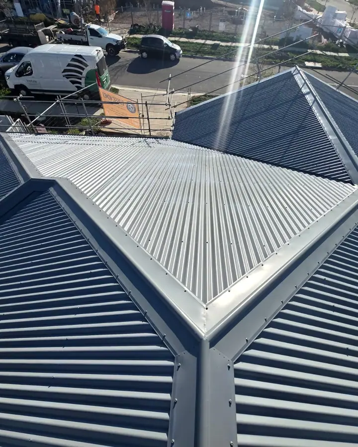 A blue grey corrugated hip roof with a lighter centre section, sun flare across the frame